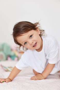 smiling cute little baby girl in white t-shirt playing in her room