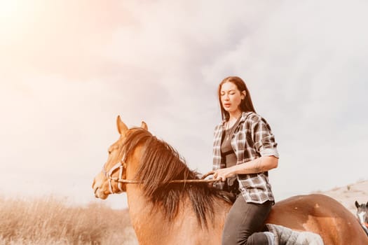 A woman in a plaid shirt rides a brown horse through a grassy field, with the sky above lit by the warm light of the sun.