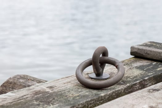 Mooring ring for boats in the port, old gray wooden pier in Baltic sea, Finland