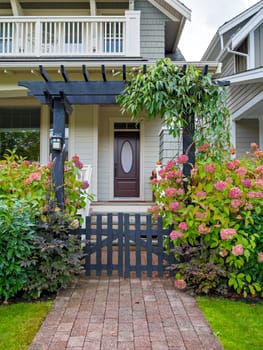 Entrance of luxury residential house with unpainted wooden gate in front.