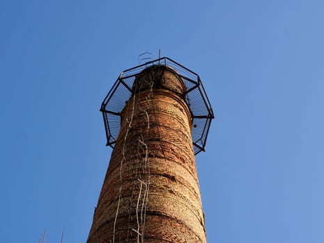 Smokestacks with ladder or stairs. Industrial tower or pipe with observation balcony. Tall brick chimneys above abandoned boiler building for venting smoke, combustion byproducts from factory heating