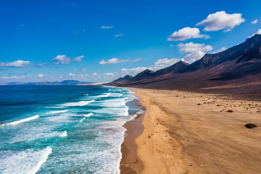 Amazing Cofete beach with endless horizon. Volcanic hills in the background and Atlantic Ocean. Cofete beach, Fuerteventura, Canary Islands, Spain. Playa de Cofete, Fuerteventura, Canary Islands.