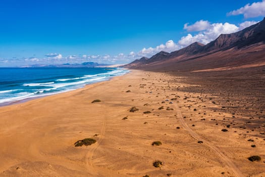 Amazing Cofete beach with endless horizon. Volcanic hills in the background and Atlantic Ocean. Cofete beach, Fuerteventura, Canary Islands, Spain. Playa de Cofete, Fuerteventura, Canary Islands.