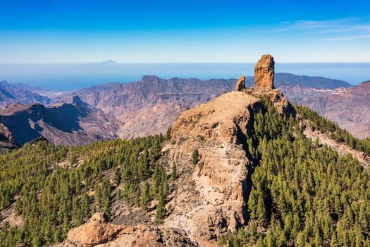 Roque Nublo and Pico de Teide in the background on Gran Canaria Island, Spain. Panoramic view of Roque Nublo sacred mountain, Roque Nublo Rural Park, Gran Canary, Canary Islands, Spain.