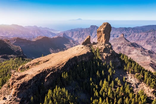 Roque Nublo and Pico de Teide in the background on Gran Canaria Island, Spain. Panoramic view of Roque Nublo sacred mountain, Roque Nublo Rural Park, Gran Canary, Canary Islands, Spain.