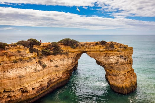 Natural arch above ocean, Arco de Albandeira, Algarve, Portugal. Stone arch at Praia de Albandeira, Lagoa, Algarve, Portugal. View of the natural arch Arco da Albandeira in the Algarve, Portugal.