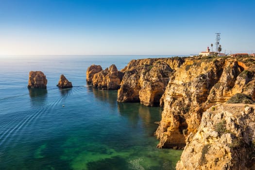 Panoramic view, Ponta da Piedade near Lagos in Algarve, Portugal. Cliff rocks and tourist boat on sea at Ponta da Piedade, Algarve region, Portugal. Ponta da Piedade, Algarve region, Portugal.