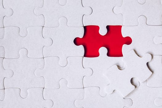 Unfinished white jigsaw puzzle pieces. Fill in pieces of the jigsaw puzzle. Complete the jigsaw puzzle with the missing pieces. Fragment of a folded white jigsaw puzzle.