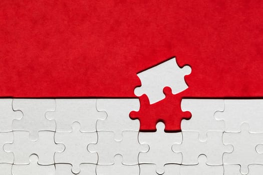 White jigsaw puzzle pieces. Fill in pieces of the jigsaw puzzle. Complete the jigsaw puzzle with the missing pieces. Fragment of a folded white jigsaw puzzle.