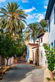 A small building with a blue door sits in front of a large Mosque with a tall tower in Nicosia, Cyprus. Beautiful street with old architecture in Nicosia, Cyprus.