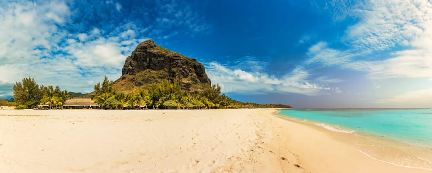 A beach with palm trees and umbrellas on Le morne Brabant beach in Mauriutius. Tropical crystal ocean with Le Morne beach and luxury beach in Mauritius. Le Morne beach with palm trees, white sand and luxury resorts, Mauritius.