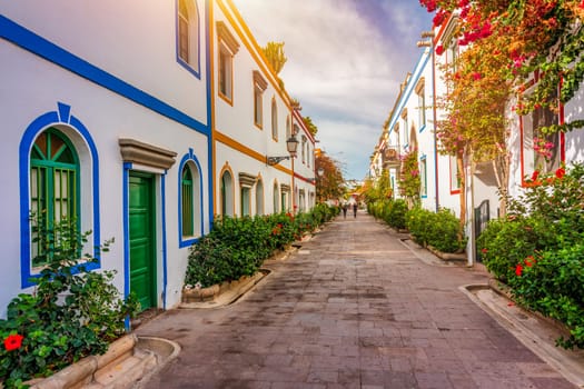 Street with blooming flowers in Puerto de Mogan, Gran Canaria, Spain. Favorite vacation place for tourists and locals on island. Puerto de Mogan with lots of bougainvillea flowers, Canary Island.