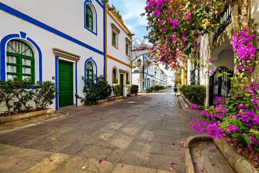 Street with blooming flowers in Puerto de Mogan, Gran Canaria, Spain. Favorite vacation place for tourists and locals on island. Puerto de Mogan with lots of bougainvillea flowers, Canary Island.