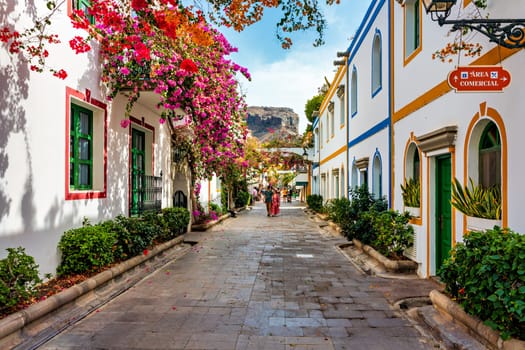 Street with blooming flowers in Puerto de Mogan, Gran Canaria, Spain. Favorite vacation place for tourists and locals on island. Puerto de Mogan with lots of bougainvillea flowers, Canary Island.