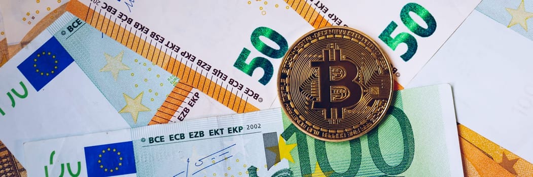 Golden bitcoin over Euro money. Bitcoin cryptocurrency. Crypto currency concept. Bitcoin with euro bills. Bitcoins stacked on euro banknotes.