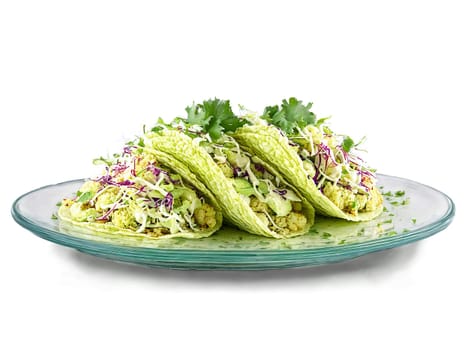 Vegan cauliflower tacos with lime crema and cabbage slaw served on a transparent glass dish. Food isolated on transparent background.