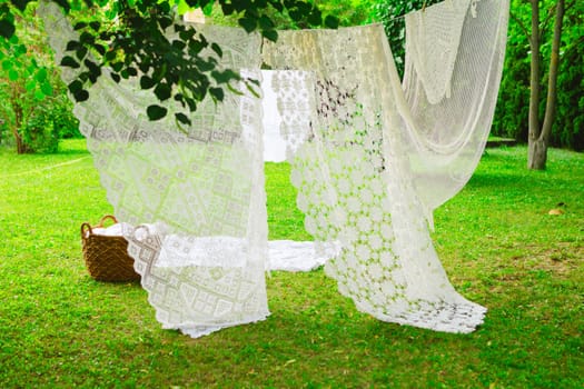 White laundry on clothesline in garden. White curtains drying in the sun