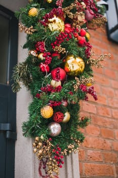 Stylish christmas fir branches with red and gold baubles on front of building holiday market in city street. Winter christmas street decor