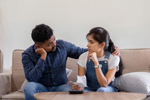 Young couple stressing about bills and invoices in living room Increased expenses cause stress..