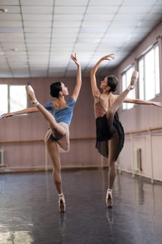 Two Asian ballerinas are dancing in the class