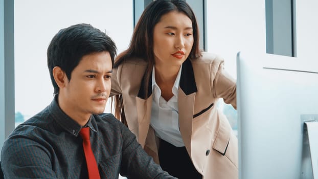 Two business people talk project strategy at office meeting room. Businessman discuss project planning with colleague at modern workplace while having conversation and advice on financial report. Jivy