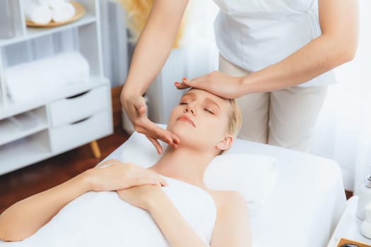 Caucasian woman enjoying relaxing anti-stress head massage and pampering facial beauty skin recreation leisure in dayspa modern light ambient at luxury resort or hotel spa salon. Quiescent