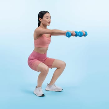 Vigorous energetic woman doing dumbbell weight lifting exercise on isolated background. Young athletic asian woman strength and endurance training session as body workout routine.