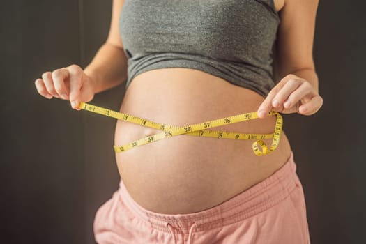 Young woman measuring her pregnant belly with inch tape. Inches, American standard. Preparation for childbirth, Girl big belly advanced healthy pregnancy.