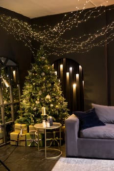 Christmas interior with a beautiful Christmas tree, sofa, light bulbs and dark background