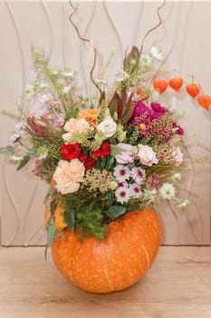 Flower arrangement in a pumpkin, autumn interior decor. Creating handmade autumn decor
