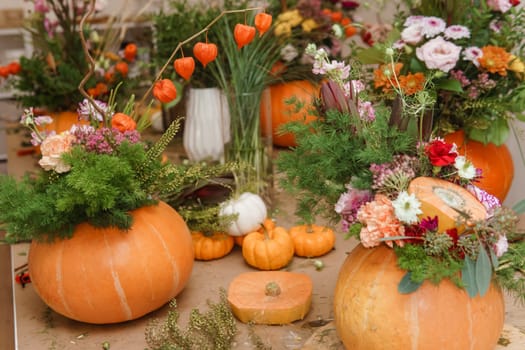 Flower arrangement in a pumpkin, autumn interior decor. Creating handmade autumn decor