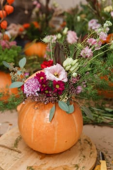 Flower arrangement in a pumpkin, autumn interior decor. Creating handmade autumn decor