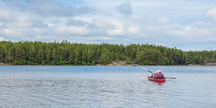 Father and son together, family activity by kayaking in the, canoeing, boating in the Baltic sea during summer vacations in Finland, horizontal banner