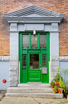 Entrance of old residential building in Vancouver decorated with flower pots.