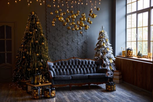 Luxurious interior of the room for Christmas and New Year. Living room in gray and gold tones with a sofa, many gifts, golden balls, ice lights, two Christmas trees