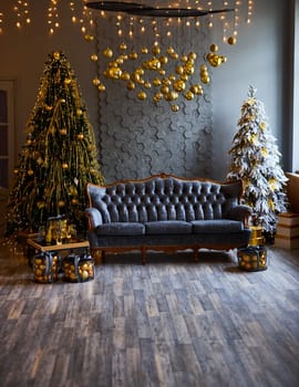 Luxurious interior of the room for Christmas and New Year. Living room in gray and gold tones with a sofa, many gifts, golden balls, ice lights, two Christmas trees