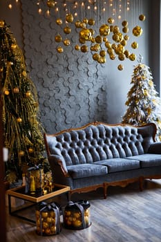 Luxurious interior of the room for Christmas and New Year. Living room in gray and gold tones with a sofa, many gifts, golden balls, ice lights, two Christmas trees
