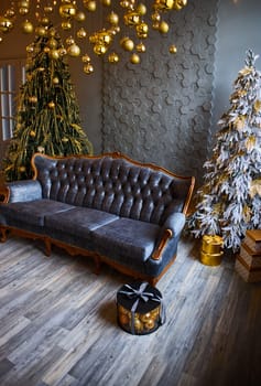 Luxurious interior of the room for Christmas and New Year. Living room in gray and gold tones with a sofa, many gifts, golden balls, ice lights, two Christmas trees