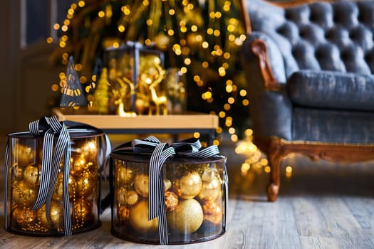Luxurious interior of the room for Christmas and New Year. Living room in gray and gold tones with a sofa, many gifts, golden balls, ice lights, two Christmas trees