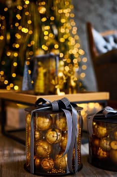 Luxurious interior of the room for Christmas and New Year. Living room in gray and gold tones with a sofa, many gifts, golden balls, ice lights, two Christmas trees