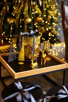 Luxurious interior of the room for Christmas and New Year. Living room in gray and gold tones with a sofa, many gifts, golden balls, ice lights, two Christmas trees
