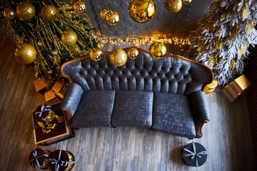 Luxurious interior of the room for Christmas and New Year. Living room in gray and gold tones with a sofa, many gifts, golden balls, ice lights, two Christmas trees. Extreme high angle shooting