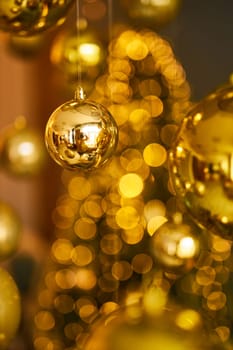 Many large golden Christmas balls look hanging against the background of the Christmas interior. Festive background in golden awards, bokeh, selective focus