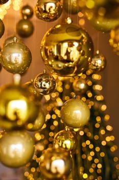 Many large golden Christmas balls look hanging against the background of the Christmas interior. Festive background in golden awards, bokeh, selective focus