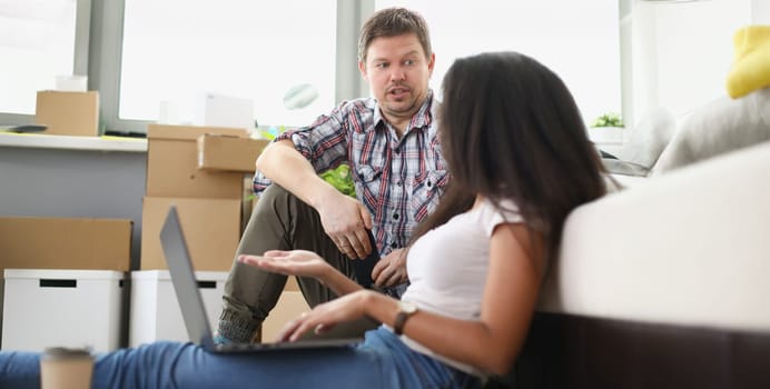 A man and a woman with a laptop are discussing the transportation of furniture, close-up. Ordering an online service for the transportation