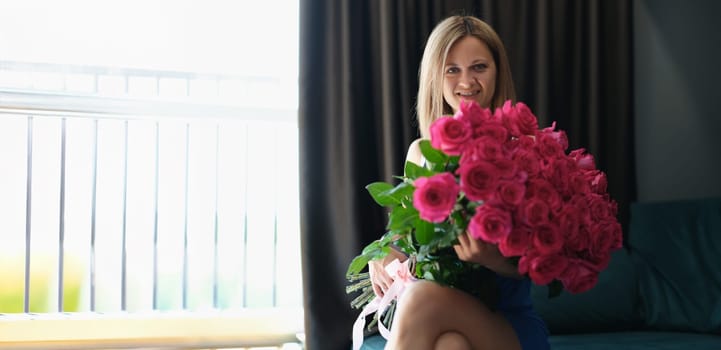 Surprised young woman with a bunch of roses on the couch, close-up. Romantic gift, wedding anniversary