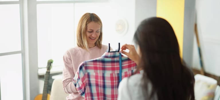 A woman seamstress shows a client a blouse in close-up, blurry. Sewing atelier, clothing designer, dressmaker