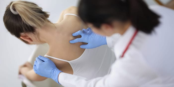 Chiropractor doctor presses on a woman's spine, close-up, top view. Osteochondrosis, physiotherapy in the clinic