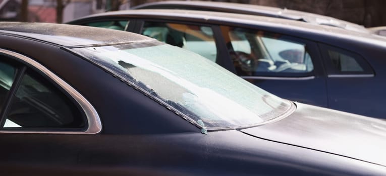 Broken rear window of a car on the street, close-up. Criminal district of the city, vandalism and theft