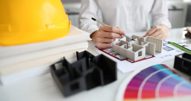 Woman designer showing 3d model of house in studio closeup. Architectural plans for apartment renovations concept